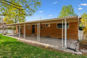 Rear view of house with a lawn, brick siding, a patio area, and entry steps