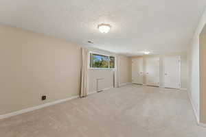 Unfurnished bedroom with visible vents, a textured ceiling, two closets, and light carpet