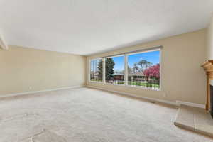 Unfurnished living room with carpet floors, baseboards, visible vents, and a fireplace
