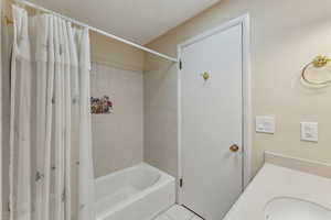 Bathroom featuring tile patterned floors, a sink, and shower / tub combo with curtain