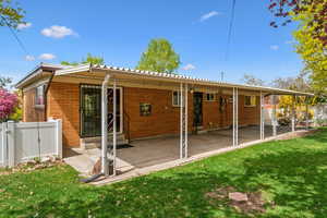 Rear view of house with a lawn, fence, brick siding, and entry steps