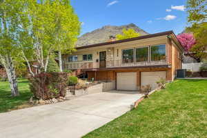 View of front facade with a garage, a front lawn, concrete driveway, a mountain view, and stairway