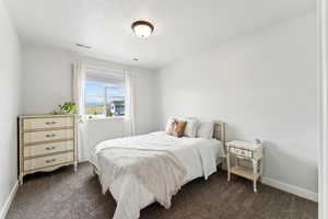 Bedroom featuring baseboards, dark carpet, a textured ceiling, and visible vents