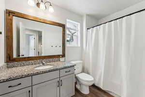 Full bath featuring toilet, a textured ceiling, wood finished floors, and vanity