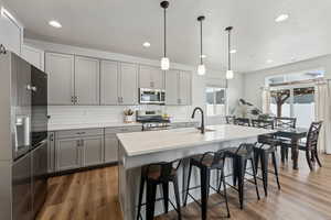 Kitchen with a sink, appliances with stainless steel finishes, gray cabinets, and tasteful backsplash