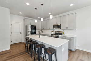 Kitchen with gray cabinetry, baseboards, appliances with stainless steel finishes, and a sink