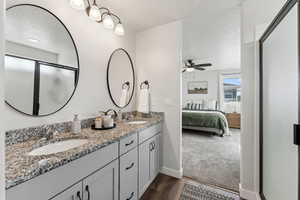 Primary bathroom with connected bathroom, ceiling fan, a sink, a textured ceiling, and wood finished floors