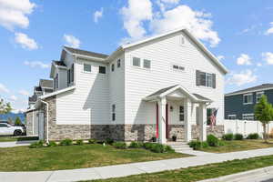 View of front of house featuring a front lawn, fence, and stone siding