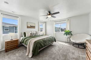 Primary Bedroom with carpet floors, a textured ceiling, ceiling fan, and visible vents