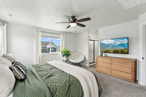 Primary bedroom with carpet, a ceiling fan, a textured ceiling, and visible vents