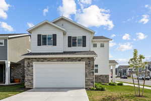 View of front of property featuring driveway, a residential view, a garage, a shingled roof, and stone siding