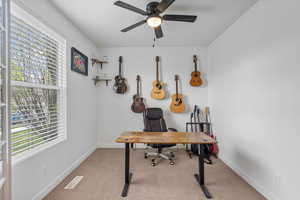 Carpeted home office featuring baseboards, a ceiling fan, and visible vents