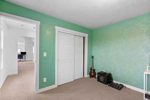 Unfurnished bedroom featuring a closet, baseboards, carpet flooring, and a textured ceiling