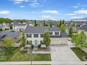 View of front of house with a front lawn, fence, a shingled roof, concrete driveway, and a residential view
