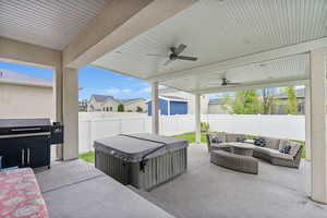 View of patio / terrace with a fenced backyard, a ceiling fan, a hot tub, and outdoor lounge area