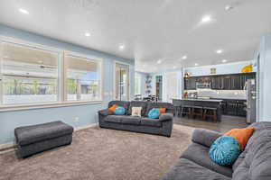 Living room with baseboards, dark colored carpet, recessed lighting, and a textured ceiling