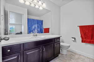Bathroom featuring vanity, baseboards, and toilet
