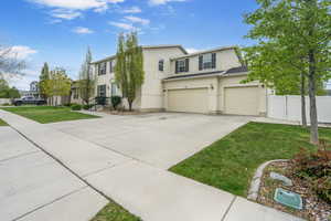 View of front of home with fence, a front lawn, concrete driveway, an attached garage, and stucco siding