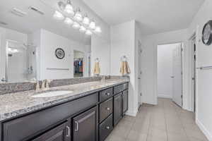 Full bathroom featuring visible vents, a sink, a stall shower, and double vanity
