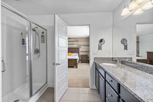 Ensuite bathroom featuring a textured ceiling, tile patterned flooring, a stall shower, vanity, and connected bathroom