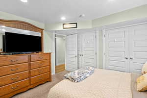Bedroom featuring light carpet, recessed lighting, and a textured ceiling