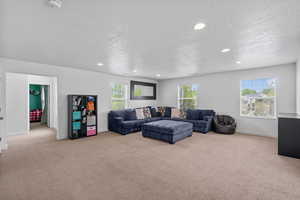 Living room with carpet floors, a textured ceiling, and baseboards