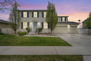 Colonial house featuring concrete driveway, fence, a gate, and stucco siding