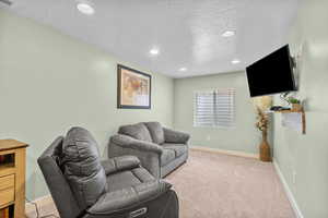 Living room featuring recessed lighting, a textured ceiling, light colored carpet, and baseboards