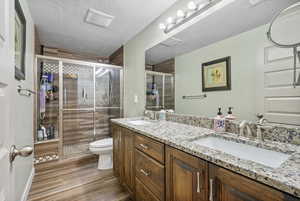 Bathroom featuring double vanity, a sink, a stall shower, and toilet