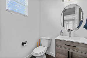 Bathroom featuring toilet, baseboards, wood finished floors, and vanity