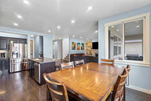 Dining area featuring a textured ceiling, a fireplace, stairway, recessed lighting, and dark wood-type flooring