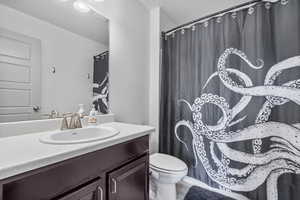 Bathroom with vanity, toilet, and a shower with curtain
