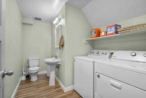 Laundry area featuring laundry area, visible vents, wood finished floors, baseboards, and separate washer and dryer