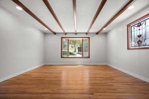 Unfurnished room with beam ceiling, recessed lighting, light wood-type flooring, and baseboards
