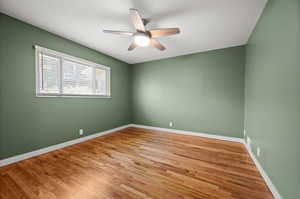 Empty room with a ceiling fan, wood finished floors, and baseboards
