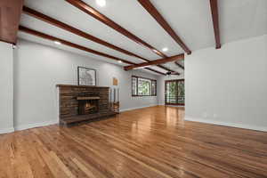 Unfurnished living room featuring a ceiling fan, light wood-style floors, beam ceiling, a fireplace, and recessed lighting