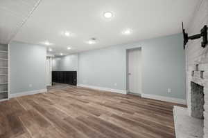 Unfurnished living room with wood finished floors, recessed lighting, a fireplace, baseboards, and a barn door