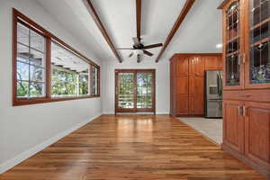 Unfurnished dining area featuring beam ceiling, ceiling fan, light wood-style floors, baseboards, and a textured ceiling