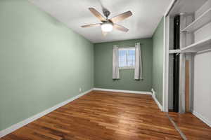 Unfurnished bedroom featuring wood finished floors, baseboards, a closet, and a ceiling fan