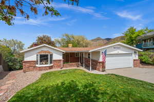 Ranch-style house featuring driveway, a chimney, a garage, brick siding, and a front lawn