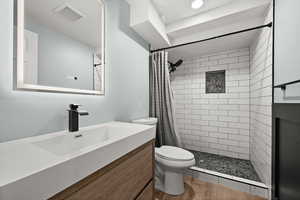 Bathroom with toilet, tiled shower, and vanity