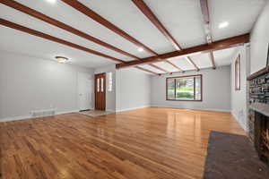 Unfurnished living room featuring a fireplace, light wood-type flooring, beam ceiling, baseboards, and recessed lighting