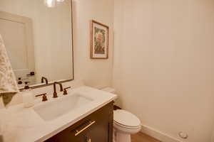 Bathroom with toilet, baseboards, wood finished floors, and vanity