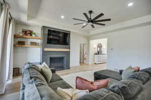 Living room with visible vents, light wood-type flooring, recessed lighting, a tray ceiling, and a ceiling fan