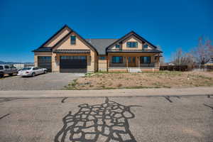 View of front of property with a porch, board and batten siding, a standing seam roof, metal roof, and gravel driveway