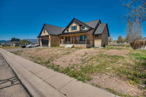 Craftsman-style house featuring fence, board and batten siding, a standing seam roof, covered porch, and metal roof