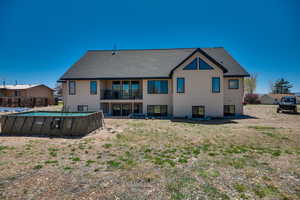 Back of property with fence, roof with shingles, stucco siding, a fenced in pool, and a balcony