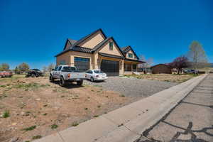 View of front of house with an attached garage, board and batten siding, a standing seam roof, driveway, and metal roof