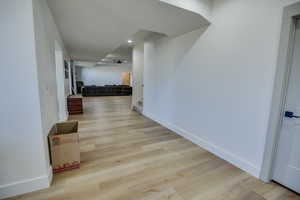 Hallway with recessed lighting, baseboards, stairway, and light wood-style floors