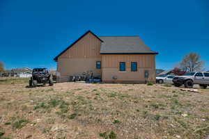 View of side of home with a shingled roof, board and batten siding, and fence